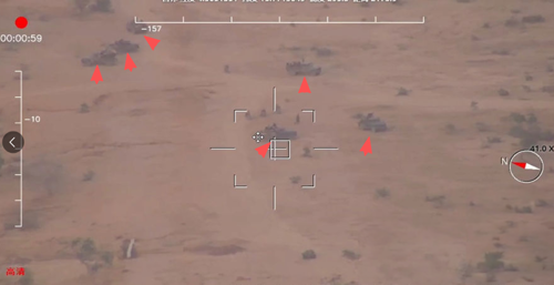 Drone footage of the desert. There are six armed vehicles travelling near a pipeline (marked by red triangles on the screenshot)