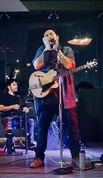 An Image of Iván Segura performing music with a microphone and a guitar